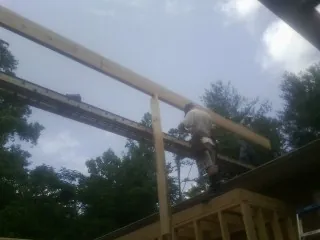 Carpenter setting a ridge beam over a new addition frame — Ice Dam Removal by Roofing Brothers in Myton