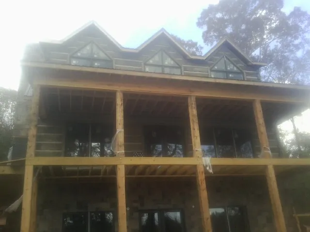 Dormers and porch framing on a large log home under construction — Roof Coating work by our crew in Myton