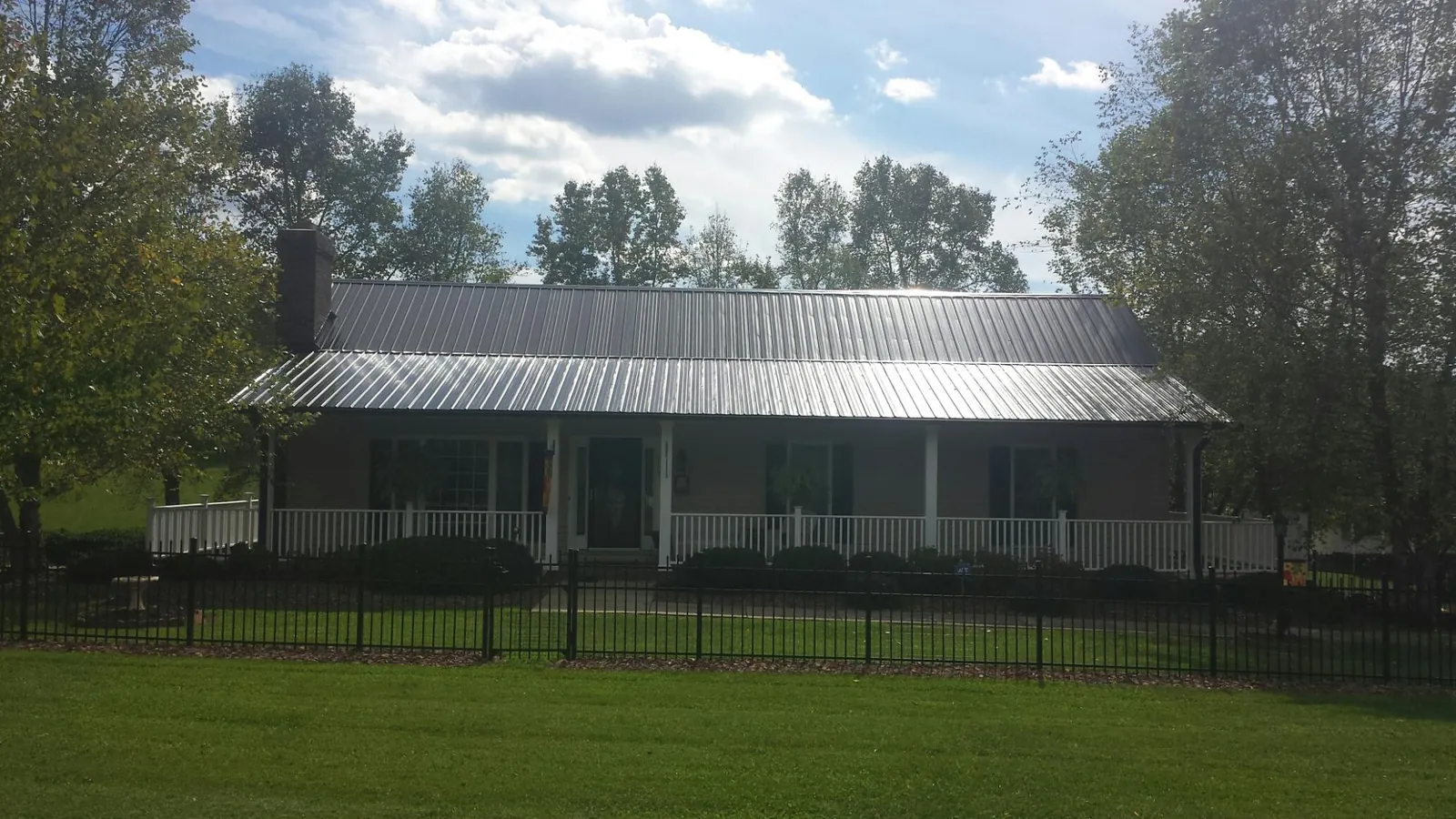 Gray metal roof on a brick ranch with a full width front porch — Gutter Guard Installation work by our crew in Myton