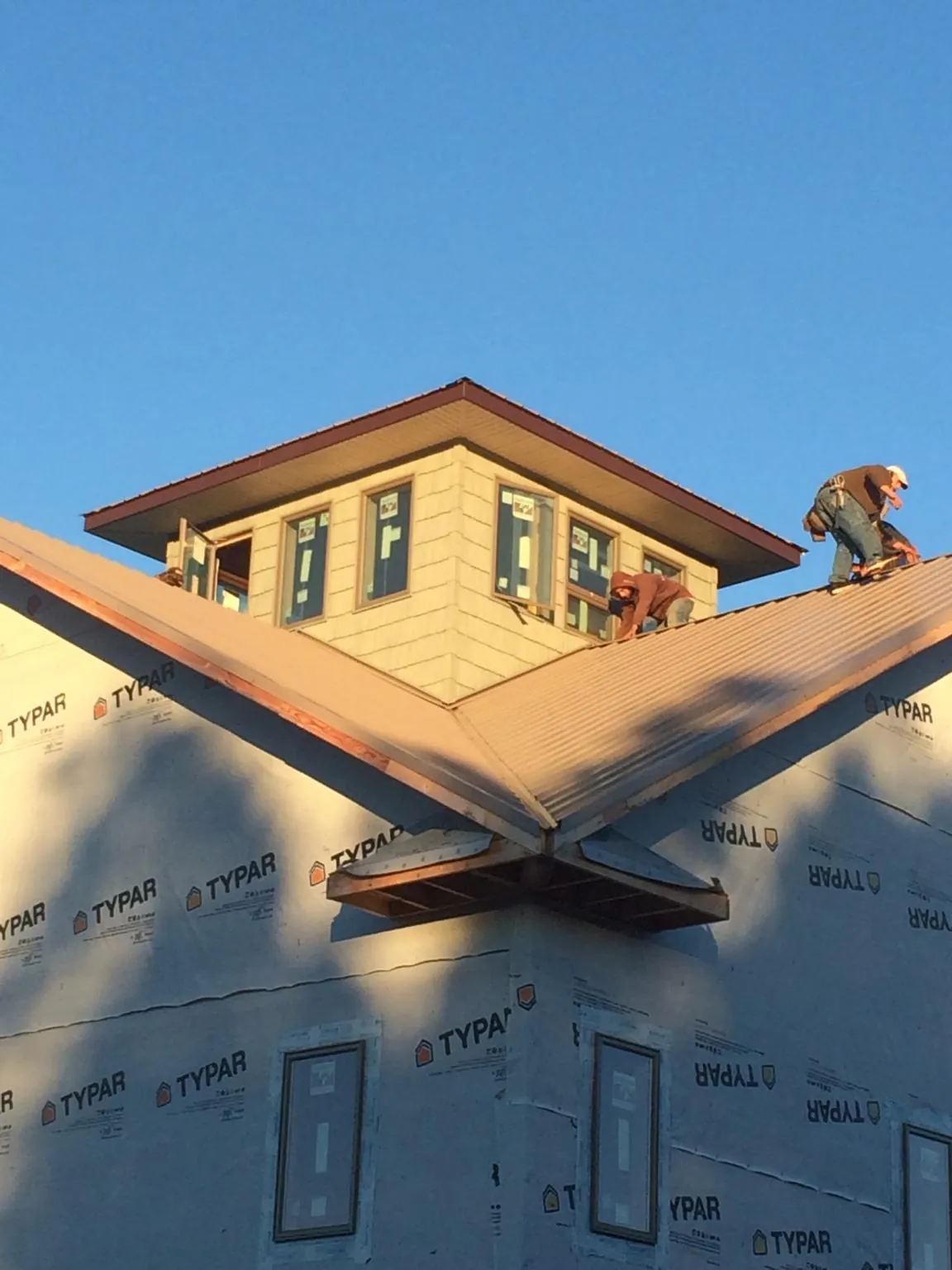 Roofers working around a rooftop cupola on a new metal roof at sunset — Roof Waterproofing in Myton by Roofing Brothers